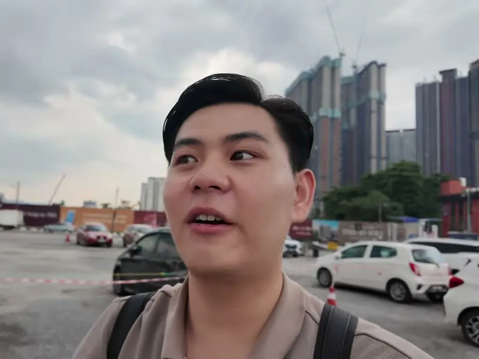 Dylan Ngan on site in Cochrane, Kuala Lumpur, with new condo towers behind him (still from his June 2026 Cochrane video)